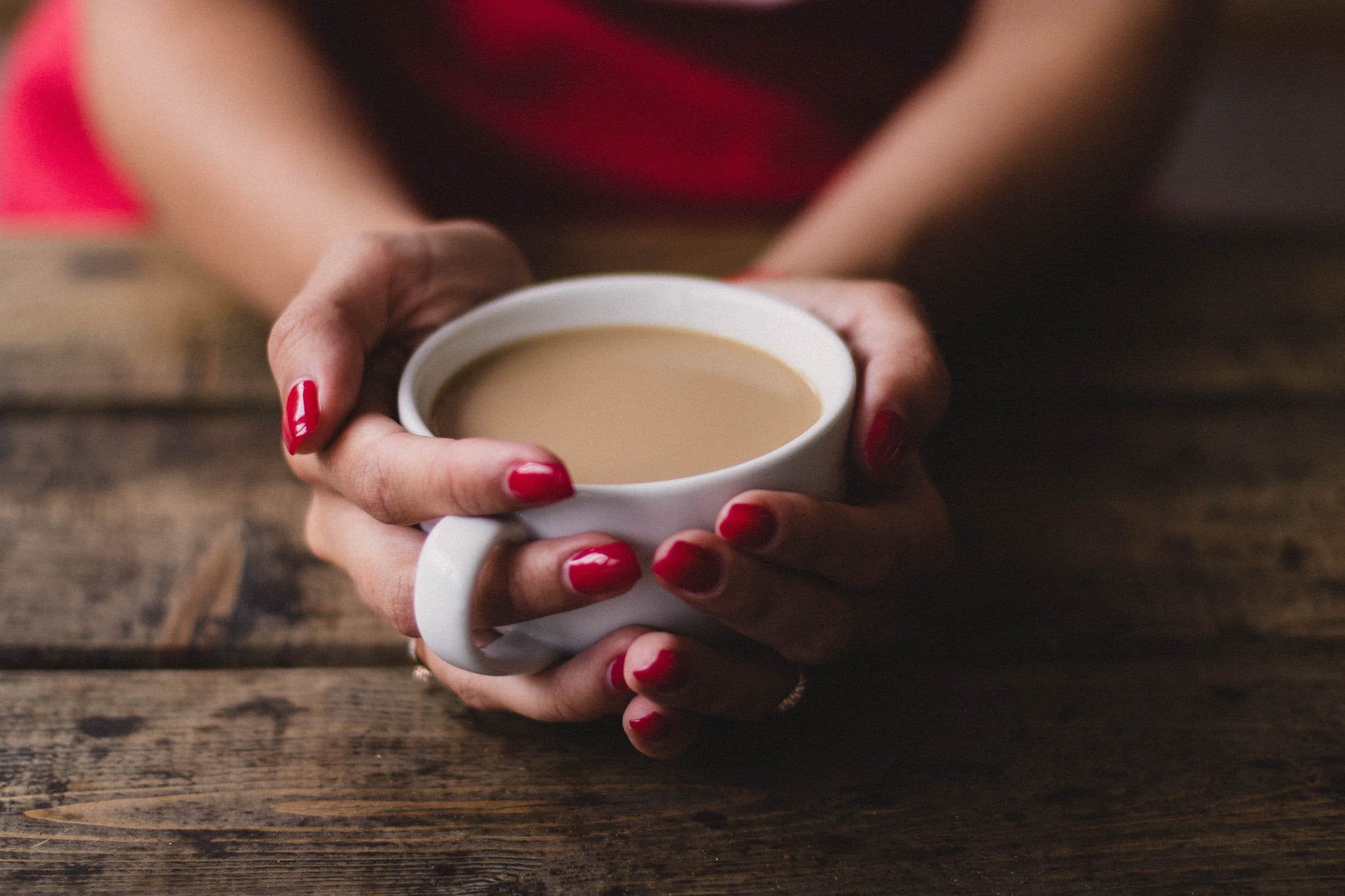 close-up of a woman's hands wrapped around a cup of coffee