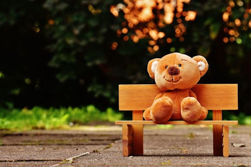 teddy bear sitting on a wood bench