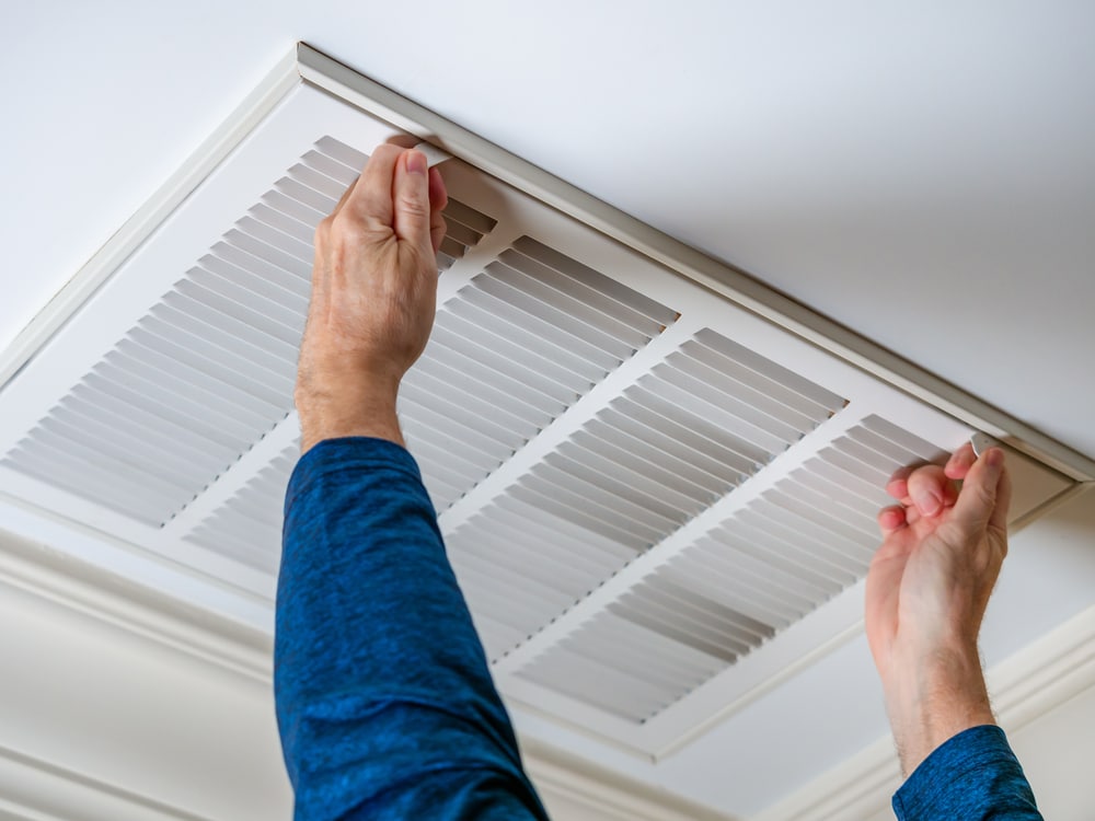 close-up of hands taking down a dirty air filter in a home